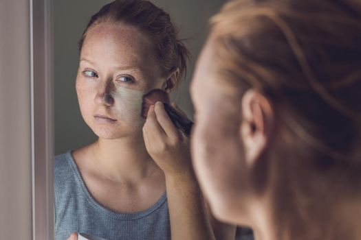 Spa Woman applying Facial green clay Mask. Beauty Treatments. Close-up portrait of beautiful girl applying facial mask.