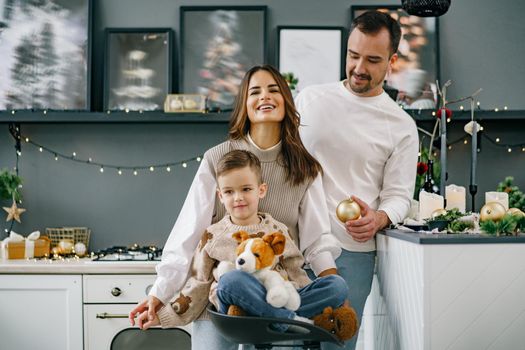 A portrait of happy family in the kitchen decorated for Christmas holidays