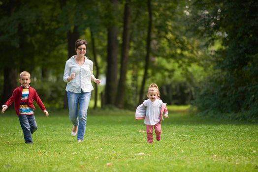 happy family playing together outdoor  in park mother with kids  running on grass