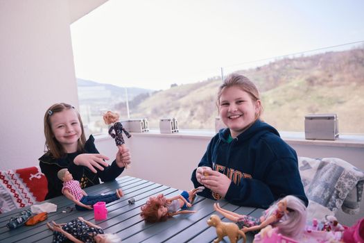sisters or friends little girls playing with dolls on balcony