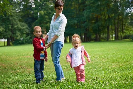 happy family playing together outdoor  in park mother with kids  running on grass