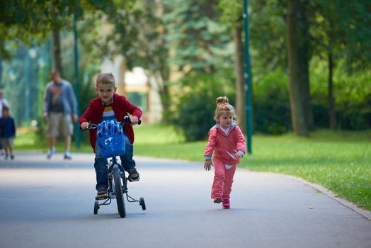 happy kids in park, boy and girl in nature with bicycle have fun