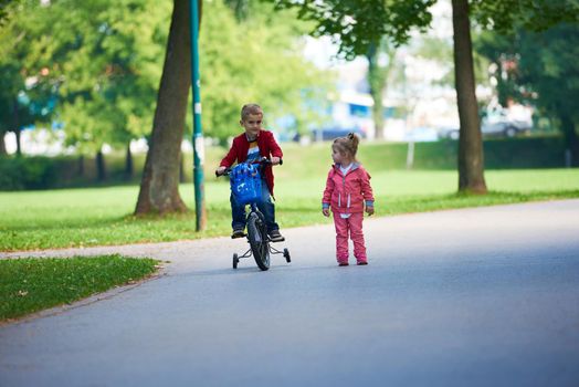 happy kids in park, boy and girl in nature with bicycle have fun