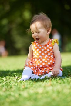 happy young baby child sittng on grass on beautiful summer day in park