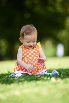 happy young baby child sittng on grass on beautiful summer day in park