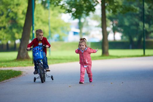 happy kids in park, boy and girl in nature with bicycle have fun