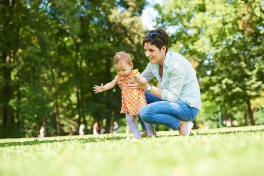 happy mother and baby child in park making first steps .  Walking and hugging.