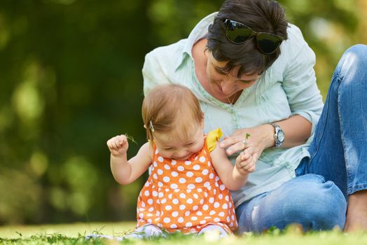 happy mother and baby child in park making first steps .  Walking and hugging.