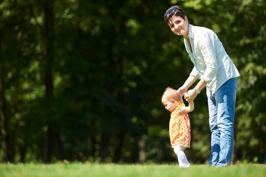 happy mother and baby child in park making first steps .  Walking and hugging.