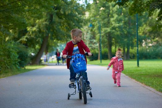 happy kids in park, boy and girl in nature with bicycle have fun