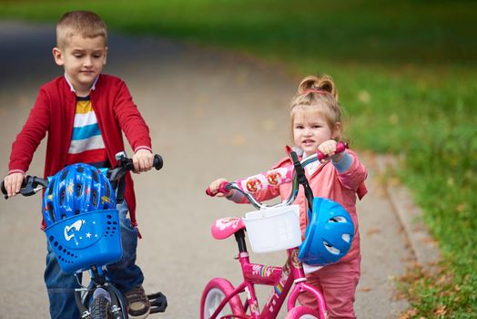 happy kids in park, boy and girl in nature with bicycle have fun