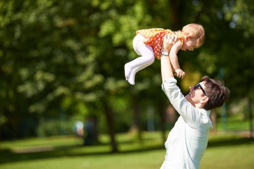 happy mother and baby child in park making first steps .  Walking and hugging.