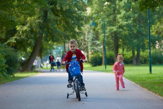 happy kids in park, boy and girl in nature with bicycle have fun