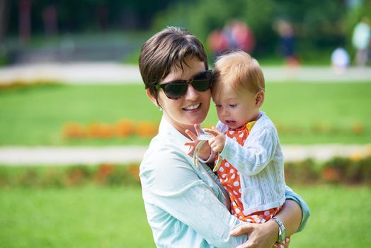 happy mother and baby child in park making first steps .  Walking and hugging.