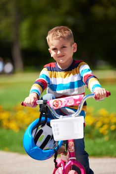 happy little boy have fun in park and learning to ride his first bike