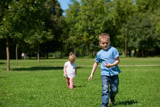 Boy and girl have fun and running. Happy child in park