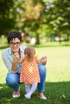 happy mother and baby child in park making first steps .  Walking and hugging.