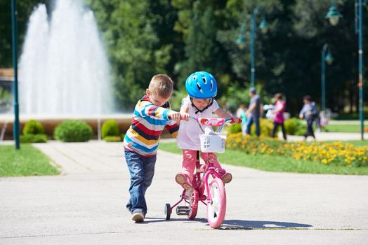 Happy childrens outdoor,  brother and sister in park have fun. Boy and girl in park learning to ride a bike.