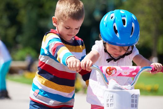 Happy childrens outdoor,  brother and sister in park have fun. Boy and girl in park learning to ride a bike.