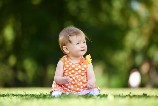 happy young baby child sittng on grass on beautiful summer day in park