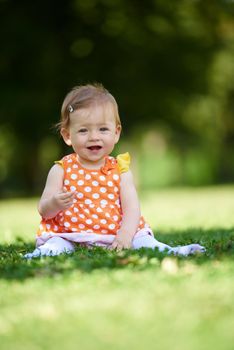 happy young baby child sittng on grass on beautiful summer day in park