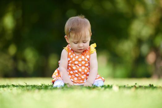 happy young baby child sittng on grass on beautiful summer day in park