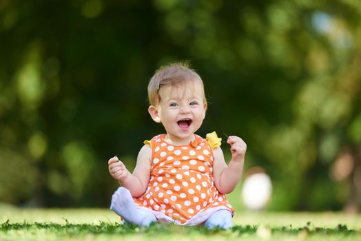 happy young baby child sittng on grass on beautiful summer day in park