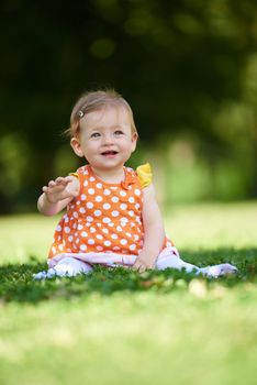 happy young baby child sittng on grass on beautiful summer day in park