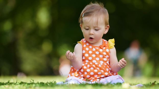 happy young baby child sittng on grass on beautiful summer day in park