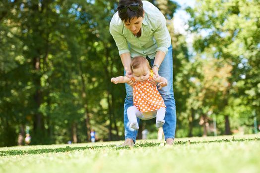 happy mother and baby child in park making first steps .  Walking and hugging.