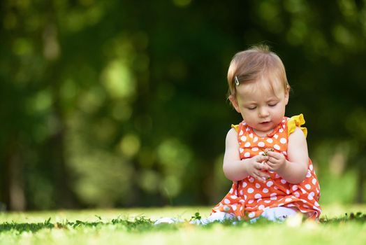 happy young baby child sittng on grass on beautiful summer day in park