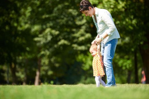 happy mother and baby child in park making first steps .  Walking and hugging.