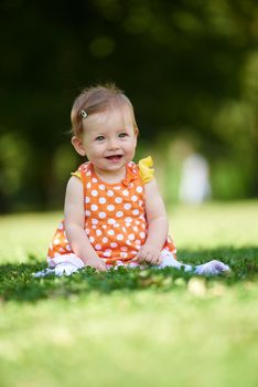 happy young baby child sittng on grass on beautiful summer day in park