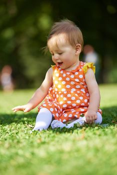 happy young baby child sittng on grass on beautiful summer day in park