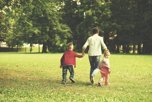 happy family playing together outdoor  in park mother with kids  running on grass