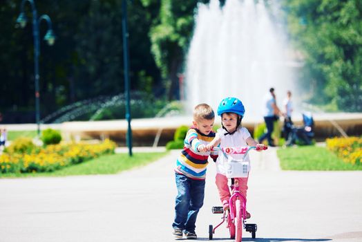 Happy childrens outdoor,  brother and sister in park have fun. Boy and girl in park learning to ride a bike.