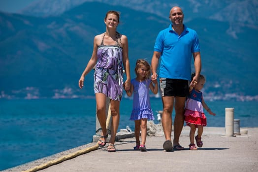 young happy family with cute little daughters holding their hands while walking by the sea during Summer vacation  Healthy family holiday concept