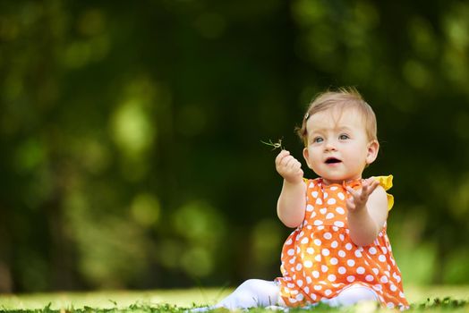 happy young baby child sittng on grass on beautiful summer day in park