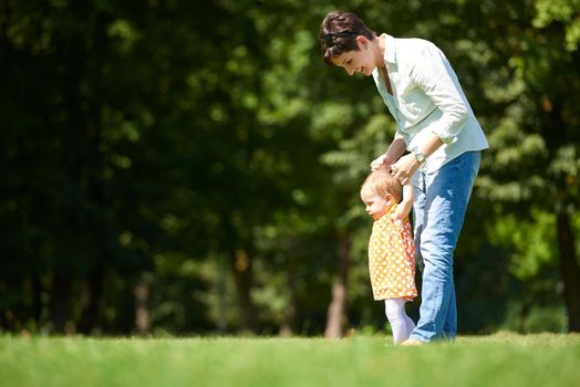 happy mother and baby child in park making first steps .  Walking and hugging.