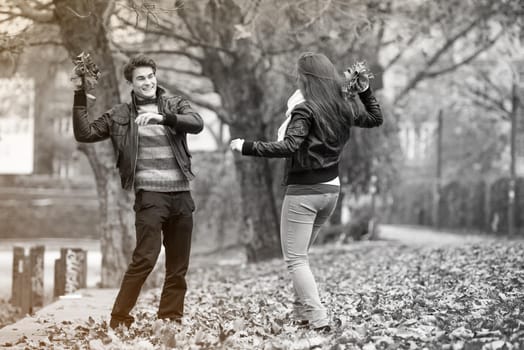 Happy young Couple in Autumn Park. Fall. Yellow Trees and Leaves. Laughing Man and Woman outside. Freedom Concept.