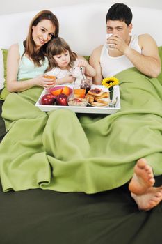 happy young family eat breakfast in bed at morning 