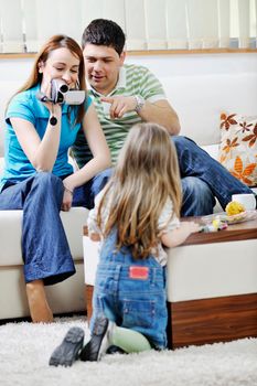 young happy family recording by video camera their child at home