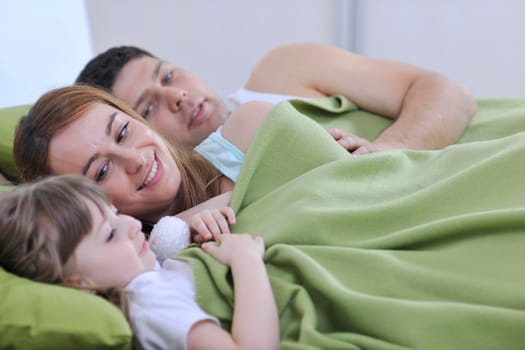 happy young family at home relaxing in bed 