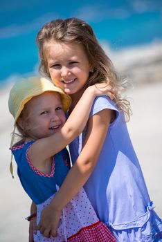 Happy smiling little sisters having fun while hugging on the beach coast during Summer vacation  Healthy childhood lifestyle concept