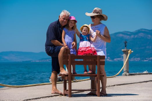 portrait of  happy grandparents with cute little granddaughters having fun on a bench by the sea during Summer vacation  Healthy family holiday concept