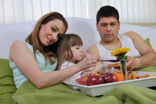 happy young family eat breakfast in bed at morning