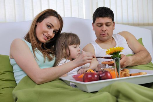 happy young family eat breakfast in bed at morning