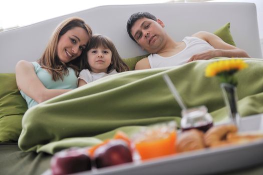 happy young family eat breakfast in bed at morning