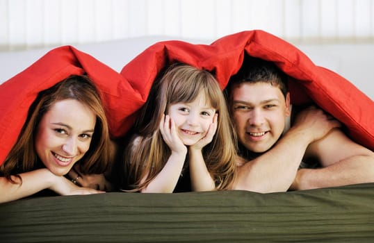 happy young family relaxing in bed 