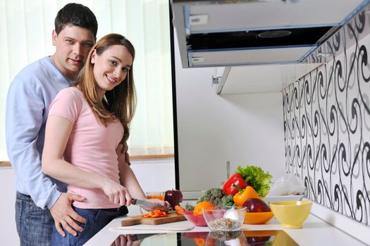 happy young couple have fun while preparing healthy fresh food in kitchen